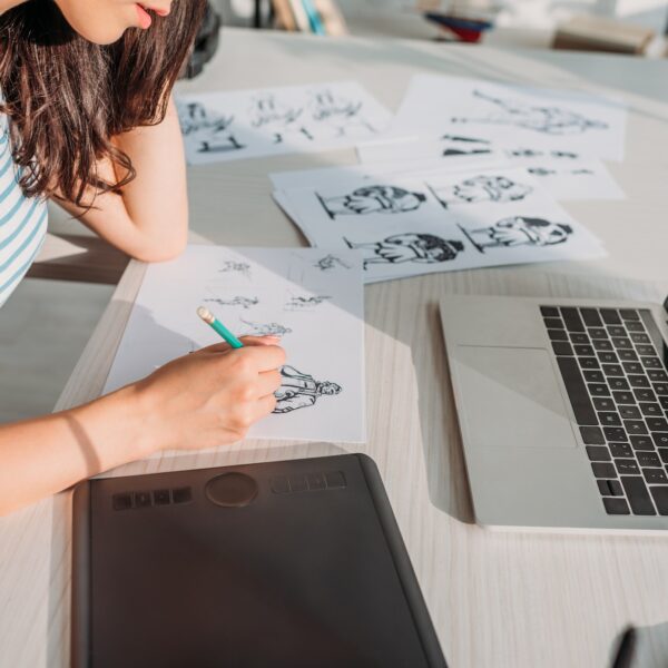 cropped view of illustrator drawing storyboard sketches in studio